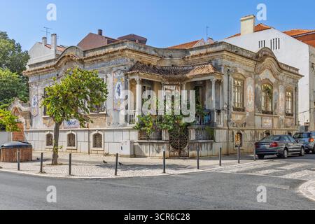 Ein altes, klassisches portugiesisches Haus an einer Ecke in Setúbal. Das Gebäude hat komplizierte Fliesendetails und eine baufällige Fassade, in der ein Baum wächst Stockfoto