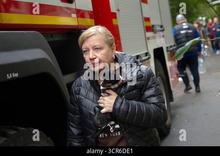 Eine Frau trägt einen Hund in den Armen nach einem russischen Streik auf ein fünfstöckiges Wohngebäude im Stadtteil Solomianskyi, bei dem am 28. September 2025 ein 12-jähriges Mädchen aus Kiew, Ukraine, getötet wurde (Foto: Kyrylo Tschubotin/Ukrinform) Stockfoto