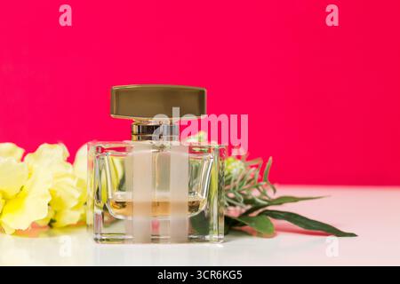 Elegante Parfümflasche mit Blumen vor einem lebendigen Hintergrund Stockfoto
