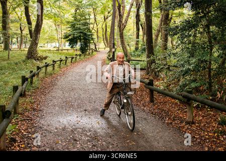 TOKIO, JAPAN - 28. OKTOBER 2024 - Horizontales Bild eines alten japanischen Mannes, der im Inokashira-Park mit dem Fahrrad fährt, während des Herbstes, der Zeit, in der der 1 Stockfoto