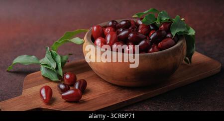 Frische Cornelianische Kirschen in rustikaler Holzschale Stockfoto