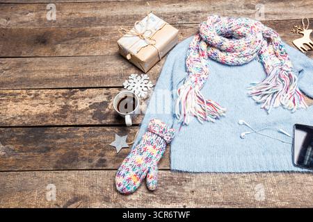 Gemütliche Winteratmosphäre mit Pullover, Kaffee und Weihnachtsgeschenken auf einem rustikalen Holztisch Stockfoto