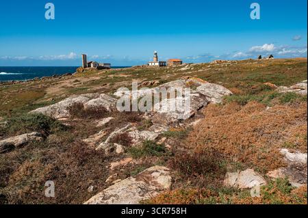 Der Leuchtturm Faro corrubedo steht vor einem klaren blauen Himmel auf dem Felsen. Weitläufige Küste der costa da Morte. Galicien. Es bietet einen ruhigen Blick auf die Stockfoto