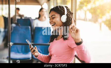 Junge Frau genießt Musik auf einer Busfahrt während eines sonnigen Tages Stockfoto