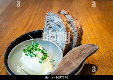 Zwei Scheiben Sauerteigbrot mit Butter an einem Esstisch in einem lokalen Restaurant in Norwegen Stockfoto