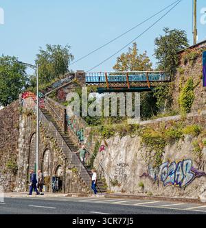 COBH, IRLAND - 15. August 2025: Historische Fußgängerbrücke und Steintreppe verbinden den oberen Cobh mit dem Hafen, der über die Bahnstrecke in der Nähe der cruis überspannt Stockfoto