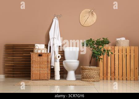 Das Innere des Toiletten mit Toilettenschüssel, Korb und Bademantel Stockfoto