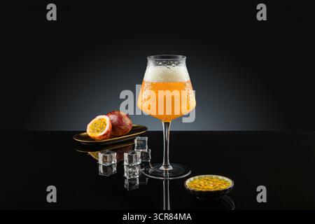 Passionsfruchtgetränk in einem Glas auf schwarzem Hintergrund mit Kopierraum. Kreative Cocktailfotografie – frische Mixgetränke für die Werbung Stockfoto
