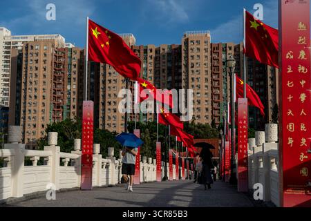 Hongkong, Hongkong. September 2025. Eine allgemeine Ansicht, die Menschen zeigt, die am 29. September 2025 in Hongkong auf einer Brücke an chinesischen Nationalflaggen vorbeilaufen. (Credit Image: © Vernon Yuen/Nexpher Images via ZUMA Press Wire) NUR REDAKTIONELLE VERWENDUNG! Nicht für kommerzielle ZWECKE! Stockfoto