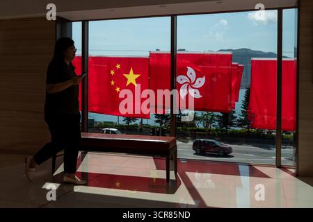 Hongkong, Hongkong. 30. September 2025. Menschen, die am 30. September 2025 in Hongkong an China National Flags und Hong Kong SAR Flags vorbeilaufen. (Credit Image: © Vernon Yuen/Nexpher Images via ZUMA Press Wire) NUR REDAKTIONELLE VERWENDUNG! Nicht für kommerzielle ZWECKE! Stockfoto