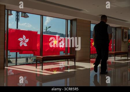 Ein man Walking Pass am 30. September 2025 in Hongkong an den China National Flags und den Hong Kong SAR Flags vorbei. (Foto von Vernon Yuen/Nexpher Images) Stockfoto