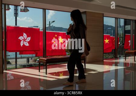 Menschen, die am 30. September 2025 in Hongkong an China National Flags und Hong Kong SAR Flags vorbeilaufen. (Foto von Vernon Yuen/Nexpher Images) Stockfoto