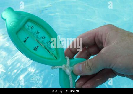 Ein Mann prüft die Temperatur an einem sonnigen Tag mit einem Thermometer. Stockfoto