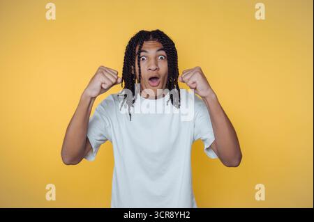Junger afroamerikanischer Mann drückt Aufregung vor hellgelbem Hintergrund aus und zeigt Freude und Begeisterung Stockfoto