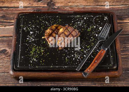 Fleischklößchen mit gegrilltem Cheddar auf einem Steinschneidebrett im Steakhouse-Restaurant Stockfoto