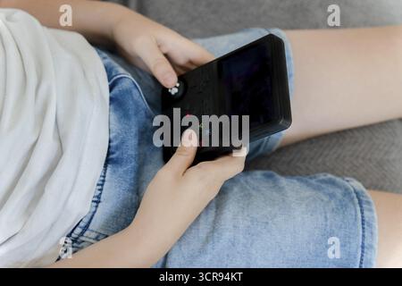 Kinderhände halten und spielen tragbare Videospielkonsole während der Freizeit Stockfoto
