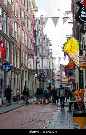 Amsterdam, Niederlande - 5. August 2025: Die Menschen schlendern entlang einer belebten Straße in Amsterdam und genießen die lebhafte Atmosphäre. Stockfoto