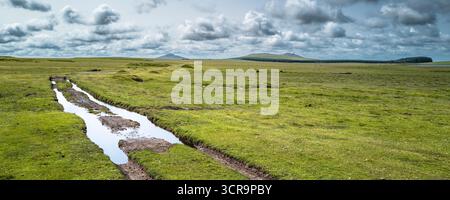 Ein Panoramabild der mit tiefem Wasser gefüllten Rutschstrecke auf dem windgepeitschten Bodmin Moor in Cornwall in Großbritannien; im Hintergrund ist Brown Willy Bronn Wennil Stockfoto