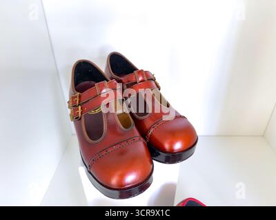 Ein Paar glänzend braune Mary Jane Lederschuhe mit Doppelriemen auf einem weißen Regal unter heller Beleuchtung Stockfoto