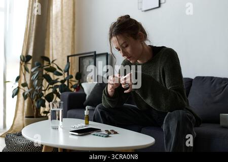 Eine junge Frau sitzt ruhig zu Hause und reflektiert ihre Gefühle, während sie von ihren Gedanken umgeben ist. Stockfoto