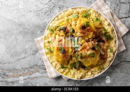 Traditionelles marokkanisches Couscous Chicken Tfaya mit karamelisierter Zwiebel und Rosinen aus der Nähe auf dem Teller auf dem Tisch. Horizontale Draufsicht von oben Stockfoto