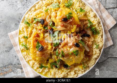 Marokkanischer Couscous Tfaya Süßer und herzhafter Couscous mit geschmortem Huhn in Nahaufnahme auf dem Teller auf dem Tisch. Horizontale Draufsicht von oben Stockfoto