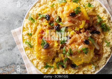 Huhn Couscous Tfaya mit karamelisierter Zwiebel und Rosinen Nahaufnahme auf dem Teller auf dem Tisch. Horizontale Draufsicht von oben Stockfoto