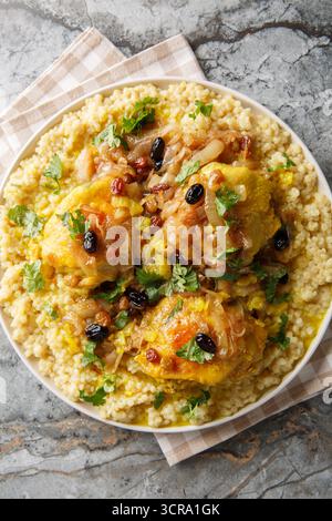 Marokkanischer Tfaya Couscous mit geschmortem Huhn auf dem Teller auf dem Tisch. Vertikale Draufsicht von oben Stockfoto