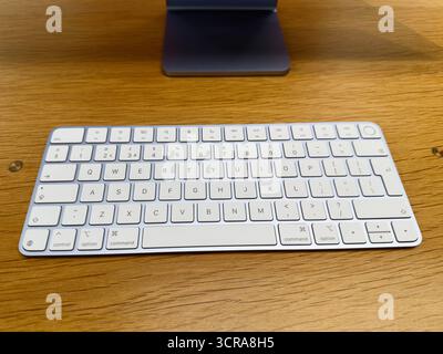 Manchester, Großbritannien – 29. September 2025: Minimalistisches Tischdesign mit weißer Apple Magic Tastatur auf Holz, die für ruhige Produktivität sorgt. Stockfoto