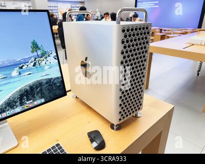 Manchester, Großbritannien - 29. September 2025: Der Mac Pro Tower neben einem großen Monitor auf einem Holztisch in einem geschäftigen Showroom. Stockfoto