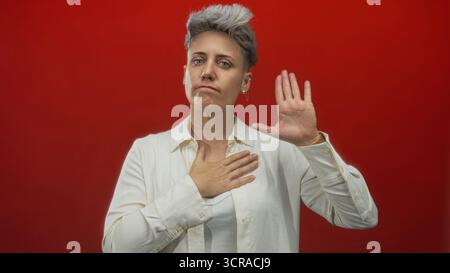 Kaukasische Frau mit kurzen Haaren, Hand auf Brust legen und Handfläche im Studio heben; Engagement. Stockfoto