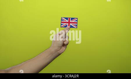 Mann mit gestickter Flagge aus großbritannien auf gelbem Hintergrund, der Nationalstolz mit Details und Einfachheit zeigt Stockfoto
