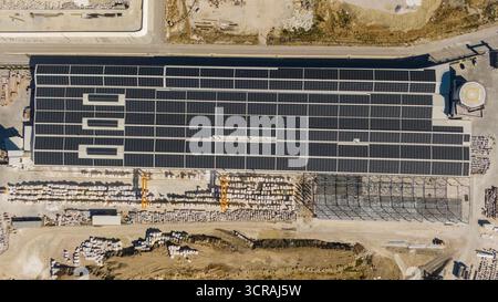 Eine Reihe von großen Solarpaneelen, die auf dem Dach eines Fabrikgebäudes montiert sind. Erneuerbare Energien und nachhaltige Industrie. Stockfoto