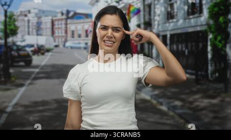 Die Frau zeigt mit dem Finger auf den Tempel auf der Straße der Stadt, während sie über Lärm und Verkehr grimmig ist; Frustration, Unglauben. Stockfoto