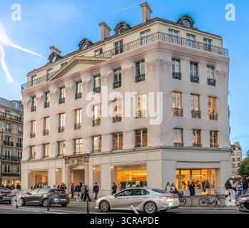 Paris, Frankreich - 09 27 2025: Eine weiße Ladenfront mit Menschen und Autos bei Sonnenuntergang Stockfoto