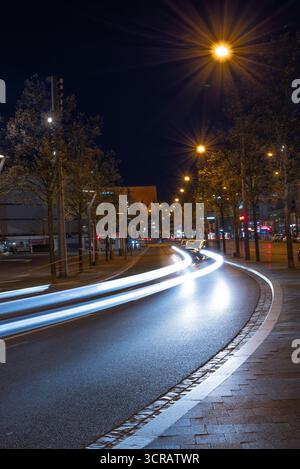 Nachtaufnahme mit langer Belichtung einer modernen Stadtstraße mit leuchtenden Straßenlaternen und hellen Lichtspuren entlang der Straße. Perfekt für Illustrationen Stockfoto