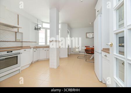 Moderne Küche mit flaschengrünen Paneelen, Messingakzenten und schwimmenden Regalen für Geschirr Stockfoto