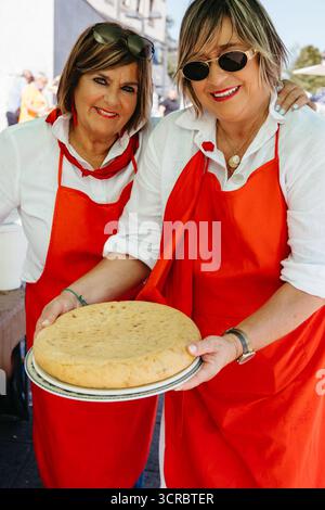 Lächelnde Frauen posieren mit einer großen Tortilla bei einer festlichen Veranstaltung im Freien Stockfoto