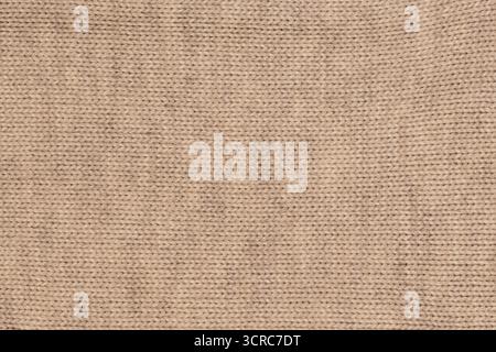 Nahaufnahme aus beigefarbenem Wollstrick mit glänzenden Fadenakzenten und detaillierten Nähten für eine weiche und leicht funkelnde Textur Stockfoto