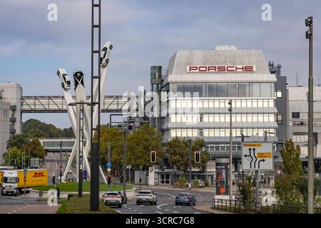 Porscheplatz, Stuttgart Zuffenhausen mit Porsche Hauptverwaltung. Kunstwerk Inspiration 911 von Gerry Judah: drei Stelen, die in bis zu 24 Meter Höhe je einen Porsche 911 präsentieren. Autotransporter mit Neuwagen. // 29.09.2025: Stuttgart, Baden-Württemberg, Deutschland *** Porscheplatz, Stuttgart Zuffenhausen mit Porsche-Hauptsitz Kunstwerk Inspiration 911 von Gerry Judah drei Stelen, jeweils bis zu 24 Meter hoch, die jeweils einen Porsche 911 Pkw-Transporter mit Neuwagen präsentieren 29 09 2025 Stuttgart, Baden Württemberg, Deutschland Stockfoto