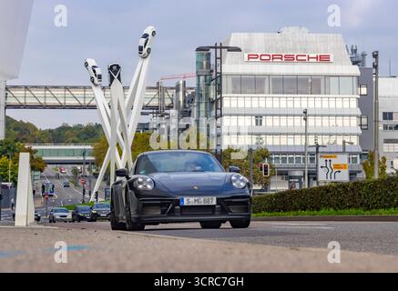 Porscheplatz, Stuttgart Zuffenhausen mit Porsche Hauptverwaltung. Kunstwerk Inspiration 911 von Gerry Judah: drei Stelen, die in bis zu 24 Meter Höhe je einen Porsche 911 präsentieren. Autotransporter mit Neuwagen. // 29.09.2025: Stuttgart, Baden-Württemberg, Deutschland *** Porscheplatz, Stuttgart Zuffenhausen mit Porsche-Hauptsitz Kunstwerk Inspiration 911 von Gerry Judah drei Stelen, jeweils bis zu 24 Meter hoch, die jeweils einen Porsche 911 Pkw-Transporter mit Neuwagen präsentieren 29 09 2025 Stuttgart, Baden Württemberg, Deutschland Stockfoto