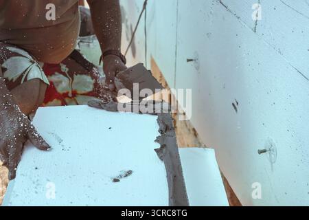 Installation der weißen Polystyrol-Wärmedämmung, Detail auf Arbeiter Hand legen grauen Kleber Zement auf weißen Brettern Stockfoto