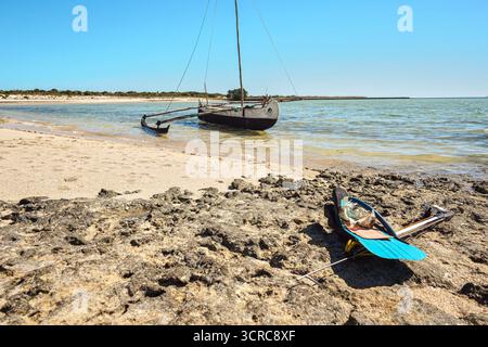 Schnorcheln, Maske, Flossen und einfache Speerfischharpune am sonnendurchfluteten felsigen Strand in der Nähe des Meeres, lokale madagassische fischer Ausrüstung, Boot bei Ebbe Wasser Backgrou Stockfoto