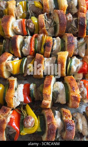 Im Ofen gebackene rustikale Spieße mit Fleisch, Wurst, Gemüse, Kräutern und Brotscheiben auf Pergamentpapier. Draufsicht. Nahaufnahme. Stockfoto