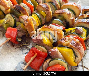 Im Ofen gebackene rustikale Spieße mit Fleisch, Wurst, Gemüse, Kräutern und Brotscheiben auf Pergamentpapier. Draufsicht. Nahaufnahme. Stockfoto