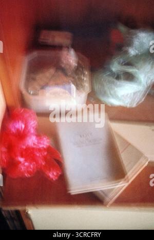 Medikamente in einer Plastikbox neben einem Buch, mit absichtlicher Bewegungsunschärfe auf Analogfilm fotografiert, was ein spontanes und leicht desorientierendes d erzeugt Stockfoto