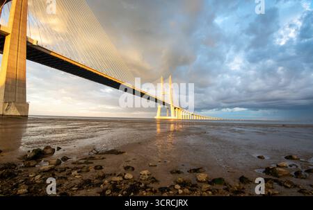 Vasco da Gama Brücke bei Sonnenuntergang mit dramatischen bewölkten Himmel in Lissabon Stockfoto