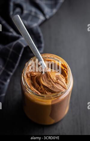 Zweifarbige Nussschokolade im Glas auf einem schwarzen Tisch. Stockfoto