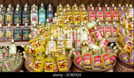 Farbenfrohe Ausstellung verschiedener in Flaschen abgefüllter Poncha-Liköre in Holzregalen in einem Geschäft, die verschiedene Aromen in lebendigen Verpackungen präsentieren. Madeira Stockfoto