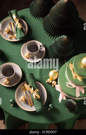 Ansicht von oben auf grünes Weihnachtsgeschirr für zwei Personen mit Geschirr und Geschenken. Gemütliche Winterkomposition mit Dekorationen. Stockfoto